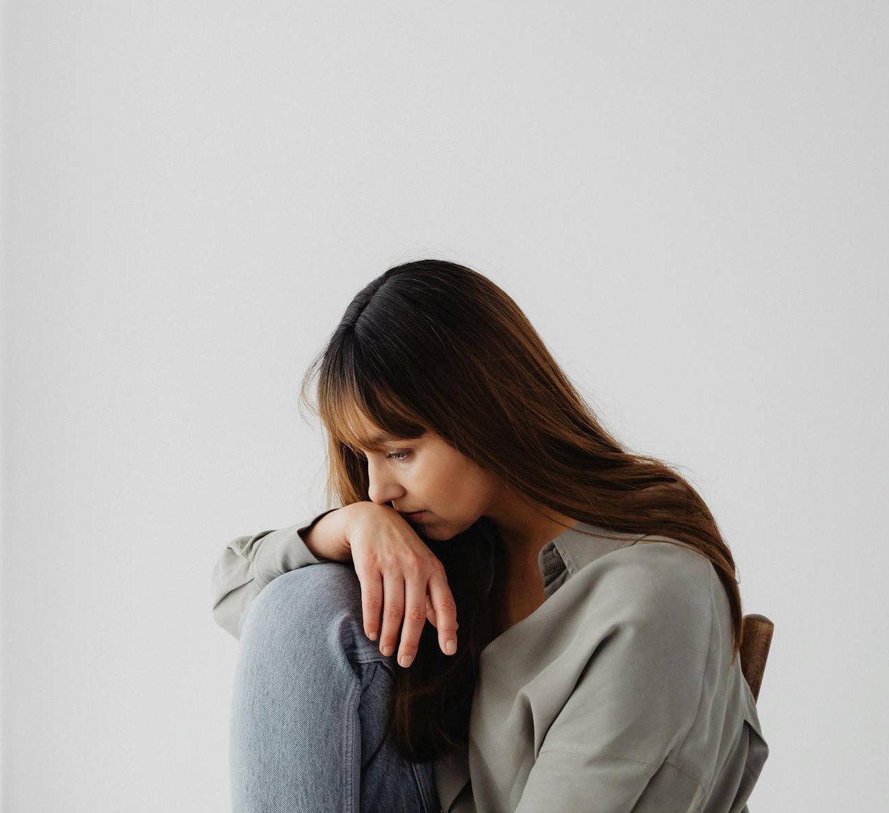 Depressed woman sitting with face and hands on her knees